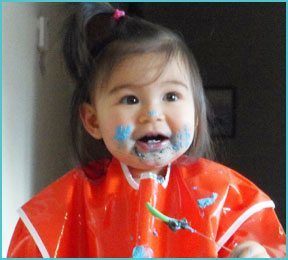 little girl with orange smock and blue pain on her face