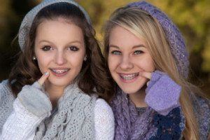 two girls pointing at their teeth while wearing braces