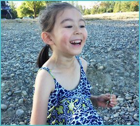 little girls in a blue and green dress outdoors smiling